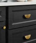 Black cabinet with brass drawer pulls in a kitchen setting