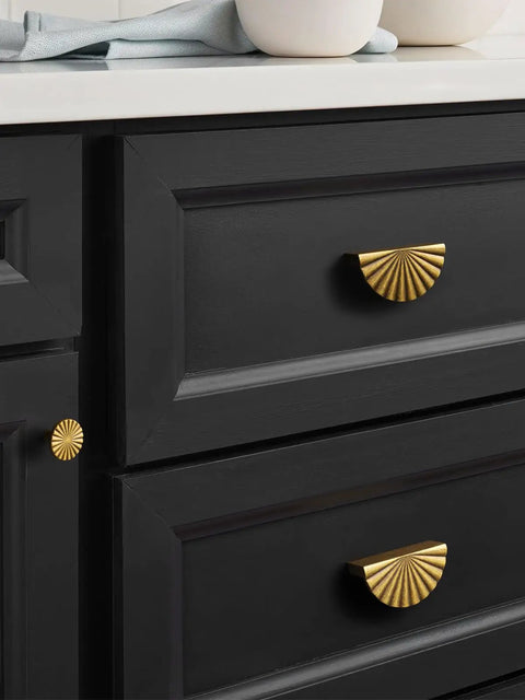 Black cabinet with brass drawer pulls in a kitchen setting