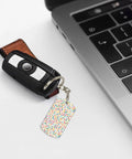 Slick Mini Abstract Rectangle Aluminum Keychain Featuring A Dope Scattered Grid Plated Finish Rust Resistant Metal Key Holder And Bag Charm Daily Accessory For Her And Him attached to a car key near a laptop.