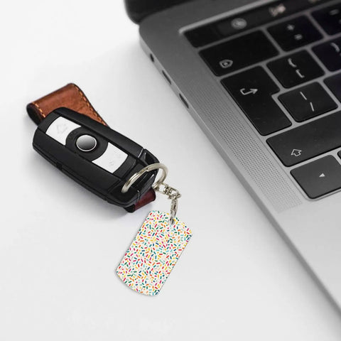 Slick Mini Abstract Rectangle Aluminum Keychain Featuring A Dope Scattered Grid Plated Finish Rust Resistant Metal Key Holder And Bag Charm Daily Accessory For Her And Him attached to a car key near a laptop.