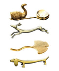 Gold-tone animal and leaf-shaped cutlery rests arranged vertically.