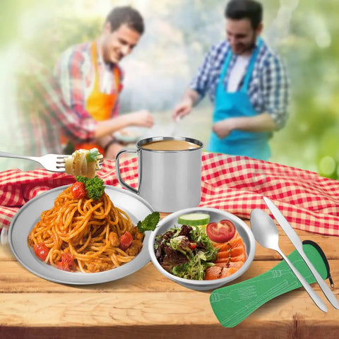 Camping Cutlery Set With Eight Piece Stainless Steel Spoons Forks Knives Plates Bowls And A Mug displayed on picnic table.