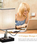 Fully Dimmable Bedside Table Lamp With Dual Phone Stands And AC Outlet Making It A Breeze To Charge Your Gadgets While You Read Sleep Or Work In Bedroom Living Room Or Study Set Of 2 Light Grey on desk with user using laptop.