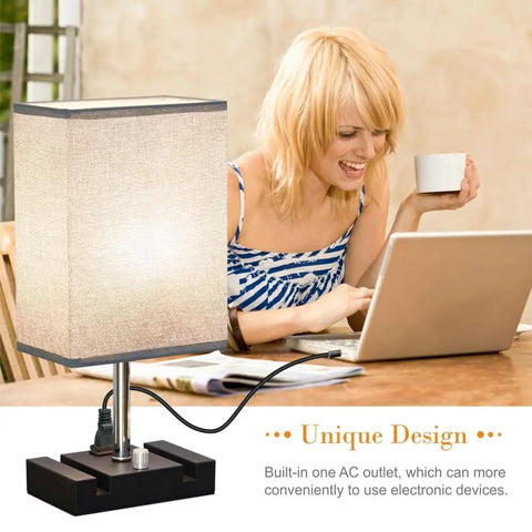Fully Dimmable Bedside Table Lamp With Dual Phone Stands And AC Outlet Making It A Breeze To Charge Your Gadgets While You Read Sleep Or Work In Bedroom Living Room Or Study Set Of 2 Light Grey on desk with user using laptop.