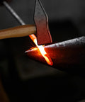 Hammer striking hot metal on anvil, showcasing use of 17 Inch Carbon Steel Blacksmith Tongs Set for precise metalworking.