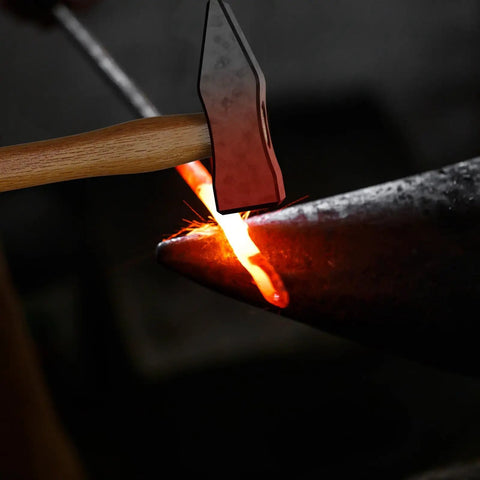 Hammer striking hot metal on anvil, showcasing use of 17 Inch Carbon Steel Blacksmith Tongs Set for precise metalworking.