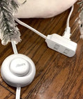 Nine Foot Three Outlet Extension Cord With Foot Switch Lets You Tap Lamps Appliances And Lighting On Or Off Perfect For Senior Living 125VAC White Pack Of Two shown on a wooden floor near snowy decor