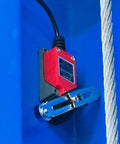 Red electric hoist unit mounted on blue bracket with steel cable for a two-post car lift.