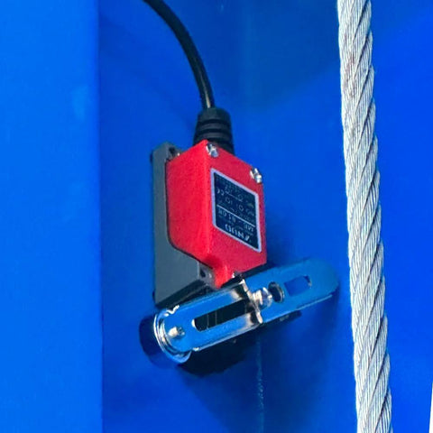 Red electric hoist unit mounted on blue bracket with steel cable for a two-post car lift.