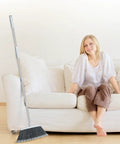 Adjustable 55 Inch Outdoor Broom For Pet Hair Removal And Heavy Duty Floor Cleaning Indoors And Outdoors next to a couch