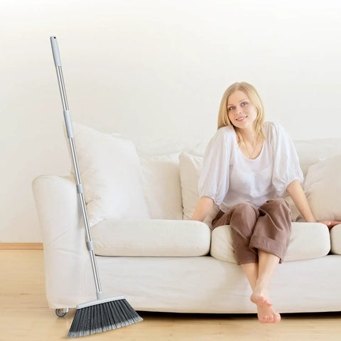 Adjustable 55 Inch Outdoor Broom For Pet Hair Removal And Heavy Duty Floor Cleaning Indoors And Outdoors next to a couch