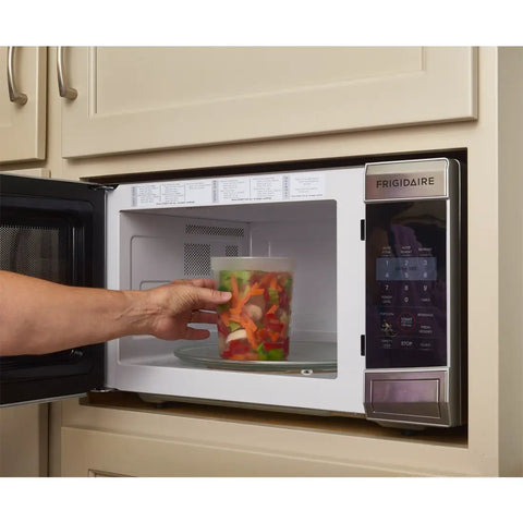 Person placing 32 Oz Deli Style Food Storage Container with lid in microwave, highlighting microwaveable Leak Proof BPA Free plastic use.