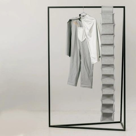Hella Handy 10 Layer Hanging Shoe Rack Saves Gobs Of Space Perfect For Boots Sneakers Hats And Bags With An Easy Fold Up Design hanging next to a gray outfit.