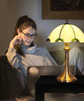 Tiffany Style Table Lamp With Yellow Stained Glass, Cozy Glow for Bedroom, 12 x 12 x 18 Inches, on table beside woman.