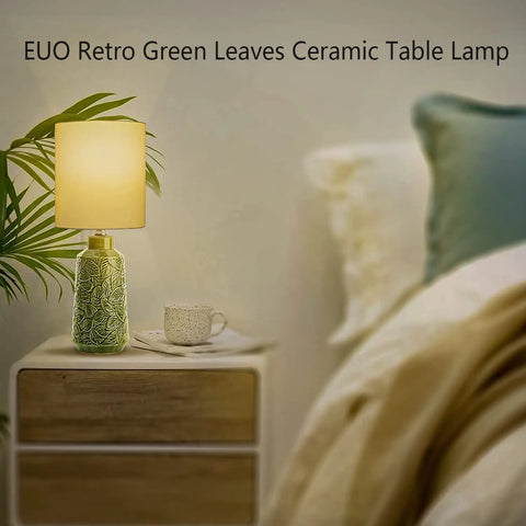 Green Ceramic Table Lamp With Leaf Pattern And White Linen Shade, 17 Inch Tall, on a bedside table