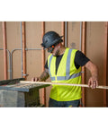 Worker wearing clear lens safety goggles with anti fog scratch resistant eye protection PPE UV shield cutting wood on job site