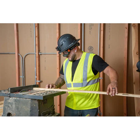 Worker wearing clear lens safety goggles with anti fog scratch resistant eye protection PPE UV shield cutting wood on job site