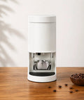 Adjustable 58mm Electric Coffee Tamper With Touchscreen Interface And Auto Sensor Activation Delivers Five To Thirty Kilograms Of Rock Solid Pressure For Sick Smooth Daily Pulls In Modern White on wooden table.