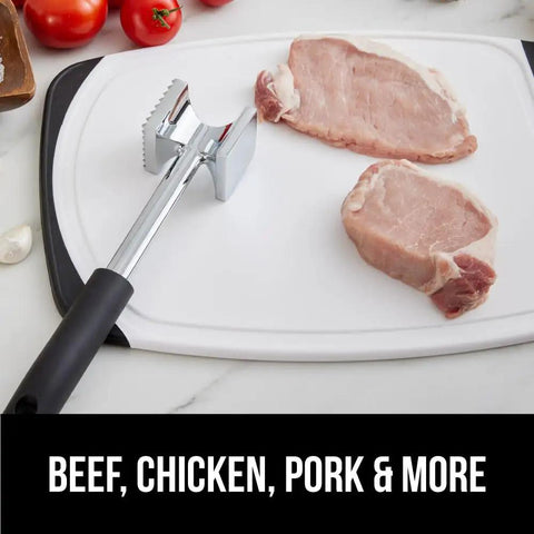 Dual Sided Meat Tenderizer Tool With Patented Design Beefy Heavy Duty Aluminum Mallet next to raw pork on cutting board