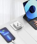 4 In 1 European Travel Plug Adapter with US Outlet and USB Ports charging phone and tablet on desk, compact white charger