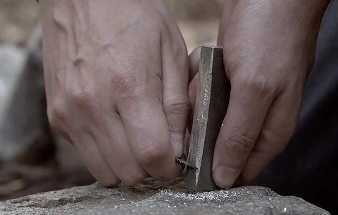Hands using Waterproof Magnesium Firestarter Kit 2 In 1 with flint serrated striker on rock, showcasing sparks for survival use.
