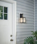 Lahden 16.75 Inch One Light Outdoor Wall Light With Clear Seeded Glass And Weathered Zinc Finish next to a white entry door