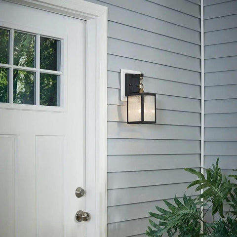 Lahden 16.75 Inch One Light Outdoor Wall Light With Clear Seeded Glass And Weathered Zinc Finish next to a white entry door