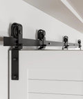 Close-up of a 60 Inch Bi Folding Sliding Barn Door Hardware Track Kit With Side Mounted Black Rollers Smooth And Quiet Operation Easy Install Door Not Included Fits Four 14 Inch Bifold Doors Heavy Duty Rated Hardware For Lasting Smooth Operation installed above a door.