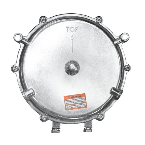 Round metallic low‑pressure gas regulator cover with bolt lugs around edge and bottom inlet fittings; top orientation mark.