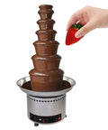 Multi Tier Chocolate Fondue Fountain With Steady Drip For House Parties And Buffets, featuring chocolate cascading, hand dipping strawberry.
