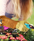 Person using Rugged Leather Work Gloves For Men And Women Built Tough Cowhide Gardening Gloves Puncture And Cut Resistant with Elbow-Length Gauntlet for gardening.