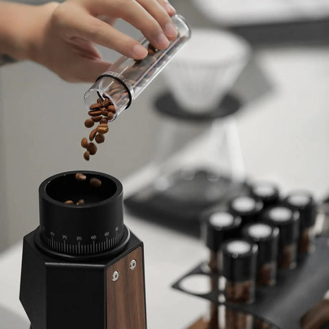 Single Dose Coffee Storage Tubes With One Way Exhaust Valve 8 Piece Set Espresso Dosing Jars And Walnut Holder pouring coffee beans.