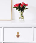 Gold modern metal cabinet door knob on white drawer, next to vase with roses. Modern Metal Cabinet Door Knobs And Wardrobe Drawer Pulls For Single Hole Install Premium Furniture Hardware For Kitchen And Bedroom Cabinets Sleek Minimalist Handle Set With Retro Charm.