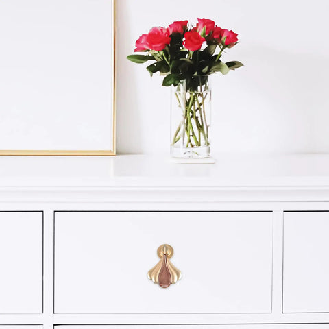 Gold modern metal cabinet door knob on white drawer, next to vase with roses. Modern Metal Cabinet Door Knobs And Wardrobe Drawer Pulls For Single Hole Install Premium Furniture Hardware For Kitchen And Bedroom Cabinets Sleek Minimalist Handle Set With Retro Charm.