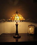 Old School Tiffany Style Geometric 2 Light Table Lamp With 16 Inch Shade And Vintage Glass Beads And Crystal Accents, lit on a wooden table