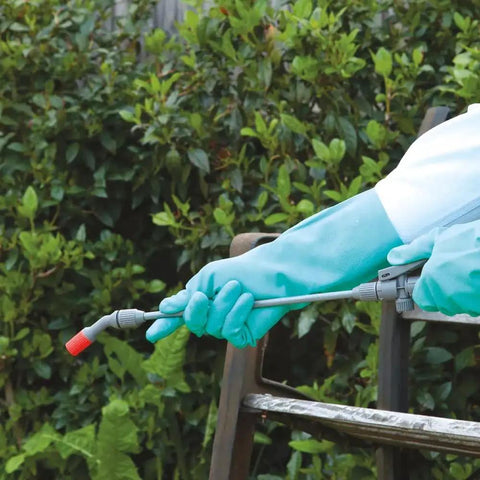 Person wearing Heavy Duty Chemical Resistant Nitrile Gloves With Cotton Flock Liner, 15 Mil Thick, using spray bottle outdoors