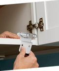 Hand installing silent self-closing cabinet hinges on white cabinet for easy and quiet operation, enhancing kitchen and bathroom furniture.