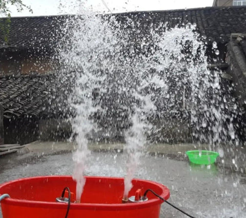 Water spraying from a red bucket using the Top Shelf 12 Volt Dc Solar Water Pump Built Like A Tank For Farm And Ranch Jobs Featuring 26 Feet Of Lift Power Plus 100 Liters Per Minute Flow Through 1 Inch Outlet Stainless Steel Submersible Design Zero Hassle Operation In Vibrant Orange Finish.