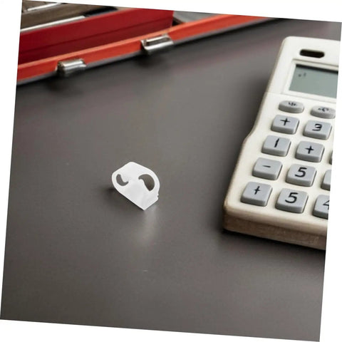 A single plastic flow control clip on desk near calculator, part of the 20 Adjustable Flow Control Clips For Tubes Plastic Hose Clamps For Precise Liquid Regulation In Labs Aquariums Home Brewing Garden Irrigation And DIY Tubing Projects.