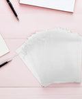 White Organza Drawstring Favor Bags Pack Of 100 Reusable Mesh Pouches for gifts on a pink desk background