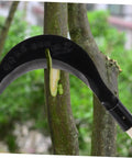 Long Handle Manganese Steel Hand Scythe for Weeding and Gardening with a comfy grip, shown cutting branch, black blade