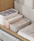 3 Piece Stackable Storage Box Set With Dividers For Bras And Leggings Multi Compartment Drawer Organizer Bin For Underwear Socks Plus Neck Ties arranged on wooden shelf with folded clothes.