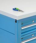 Heavy Duty 72 By 36 Inch Workbench With 1 1/4 Inch Thick ESD Laminate Top And Rock Solid Blue Steel Base Featuring Quick Height Adjust Legs For A Massive Five Thousand Pound Garage Capacity showing blue steel drawers and white laminate top with pliers.