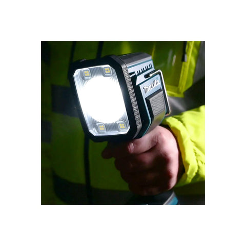 Person holding 18V LXT Cordless LED Flashlight Spotlight With Four Modes 600 Lumens Spot 1000 Lumens Flood 1250 Lumens Spot Flood And Strobe Reaches 700 Yards Up To 7 Hours Run Time With 5Ah Battery Ideal For Jobsite Camping And Auto Repair shining bright.