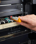 Close-up of FiberLert-125 fiber optic tester/detector (orange/gray) held near fiber cables