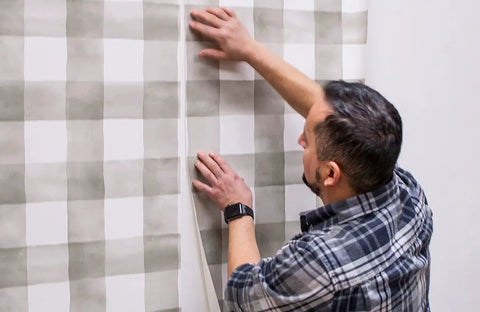 Man applying wallpaper using PRO 555 Extreme Tack Wallpaper Adhesive Paste Built For Hard To Hold Wallcoverings Permanent Bond