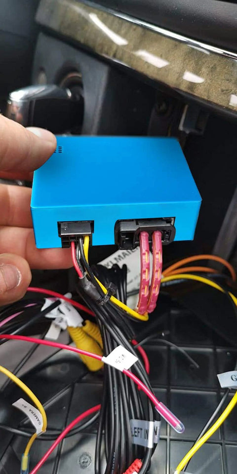 Front view of blue rectangular optic fiber decoder module with plugged-in wiring harnesses in a car dashboard