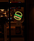 Neon burger sign glowing inside fast-food restaurant window at night