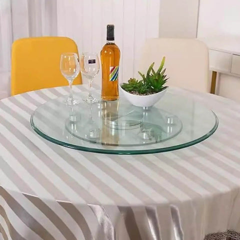 Clear Tempered Glass Lazy Susan Turntable With Silent Bearings And Six Smooth Rolling Wheels For Effortless 360 Spin On Your Kitchen Or Dining Table Making Serve Up Meals A Total Breeze At Home on a table with wine and decorations.