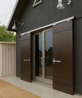 Exterior view of a sliding barn door system on a modern garage. Visible are sliding tracks and wooden doors on a dark building facade.
